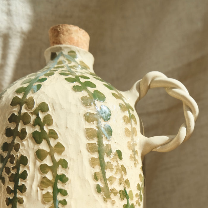 Ceramic bottle with green leaf patterns and a twisted handle